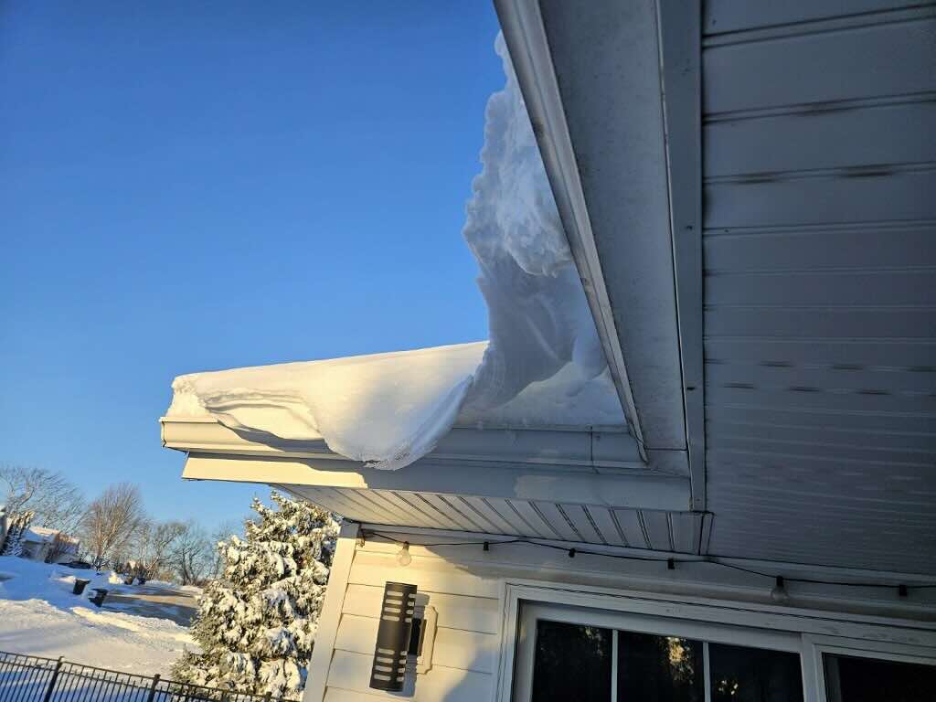 Heavy snow draping over a roof above a porch in Rock County, Wisconsin